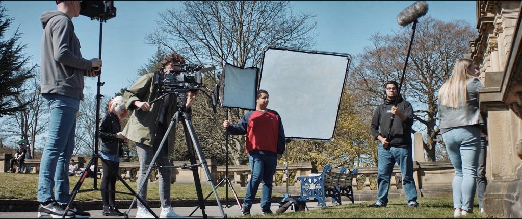 Students working as a film crew in a park