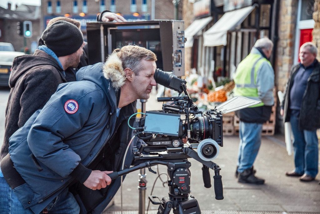 A camera operator filming outside a greengrocer on a high street
