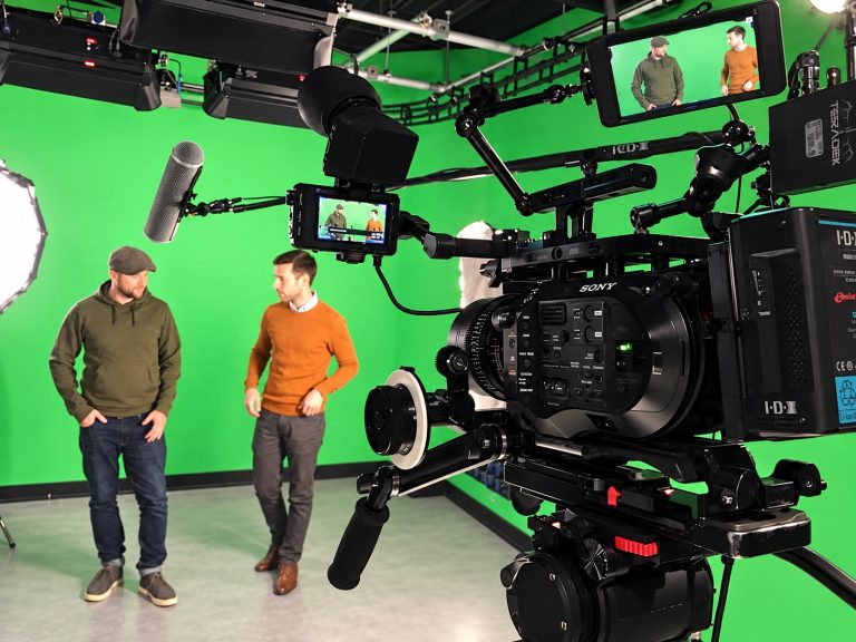 Two people being filmed against a green screen in a studio