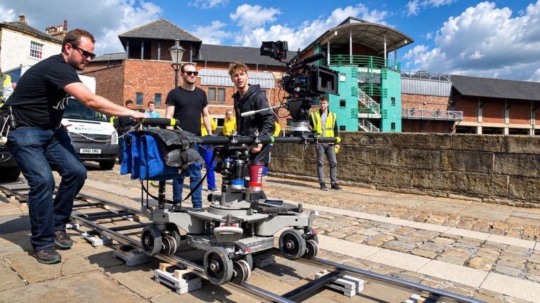 A TV ad crew moving a camera along track on location